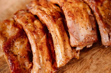 Baharatlı domuz pirzolası ile birlikte ahşap bir kesme tahtasının üzerinde cam bir pişirme çarşafında kızartılmış.