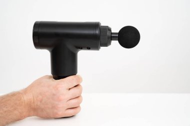 mens hands holds a massage gun. medical-sports device.  clipart