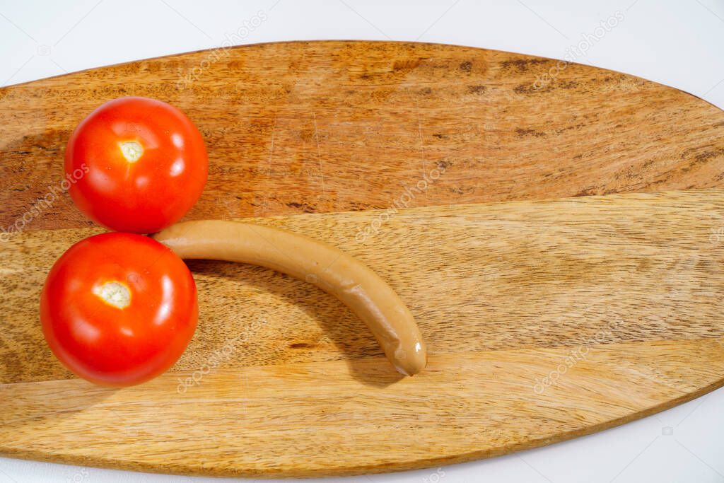 tomatoes and sausage in the form of a male penis on a wooden cutting board