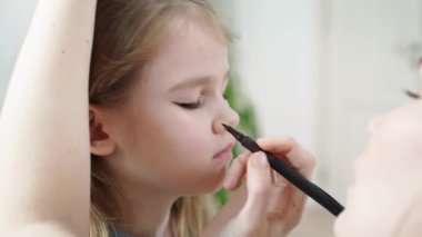 Annem makyaj yapıyor kızım, sahnede oynamak için göz kapaklarına oklar çiziyor.. 