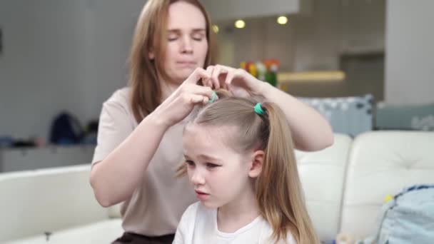 Mamma kammar sin dotter och gör två svansar, skynda, det visar sig inte omedelbart. — Stockvideo