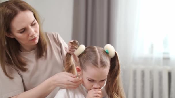 Mamá hace el peinado su hija, de prisa, resulta no inmediatamente. — Vídeos de Stock