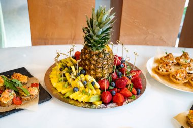 Bir tabakta ananas ve çeşitli meyveler. Güzel yemek servisi.. 