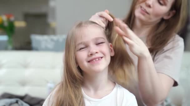 Mãe penteia sua filha e faz duas caudas, pressa, acontece que não imediatamente. — Vídeo de Stock