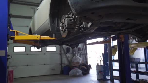 Servicio de coches. coche sube en ascensor con ruedas removidas para reparar chasis. — Vídeos de Stock