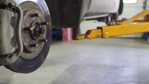 El coche sube al ascensor con las ruedas removidas para reparar el chasis. — Vídeos de Stock