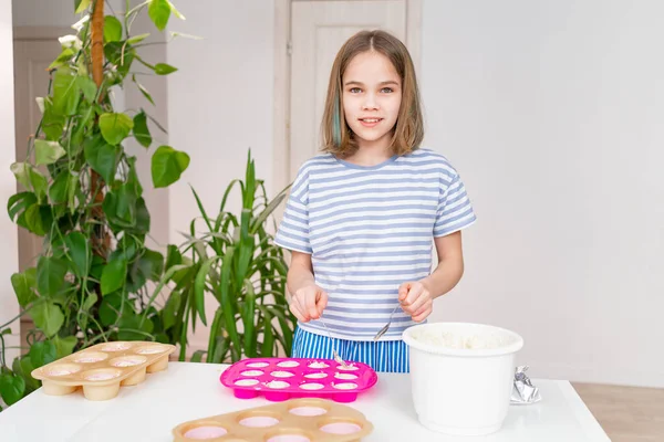 예쁜 십 대 소녀가 컵 케익을 만들기 위해 실리콘으로 반죽을 만듭니다. — 스톡 사진