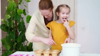 Anne ve kızı birlikte kek pişirir ve hamurun tadına bakarlar. 
