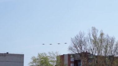 Apartman binalarının üstündeki mavi gökyüzünde savaş uçakları. Hava gösterisi.