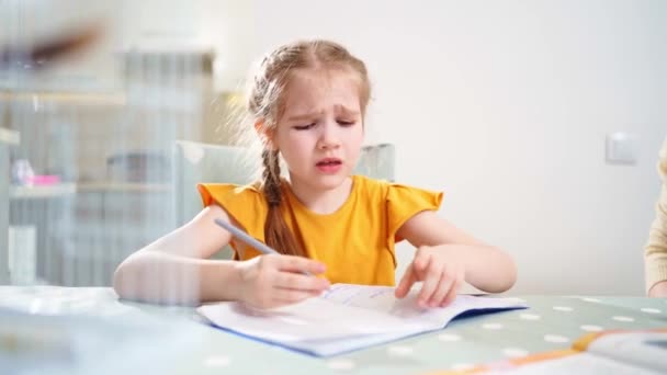Een schoolmeisje doet huiswerk en huilt. moeder zit naast haar legt uit — Stockvideo