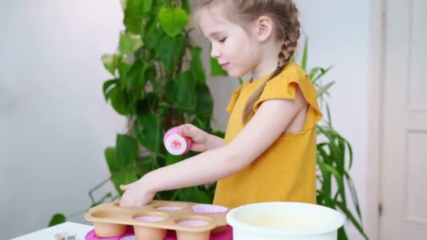 Klein meisje zet papieren manden in siliconen vorm voor cupcakes. — Stockvideo