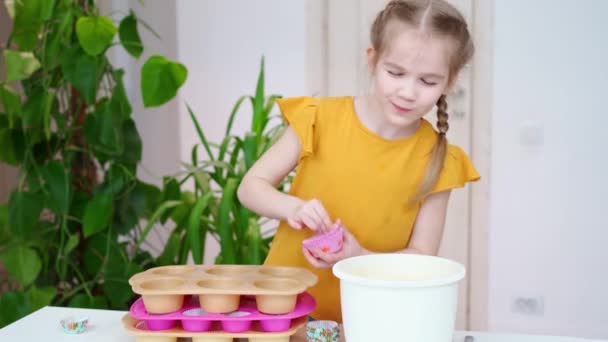 Kleines Mädchen legt Papierkörbe in Silikonform für Cupcakes. — Stockvideo