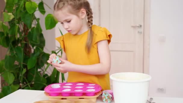 Liten flicka sätter papperskorgar i silikon form för cupcakes. — Stockvideo