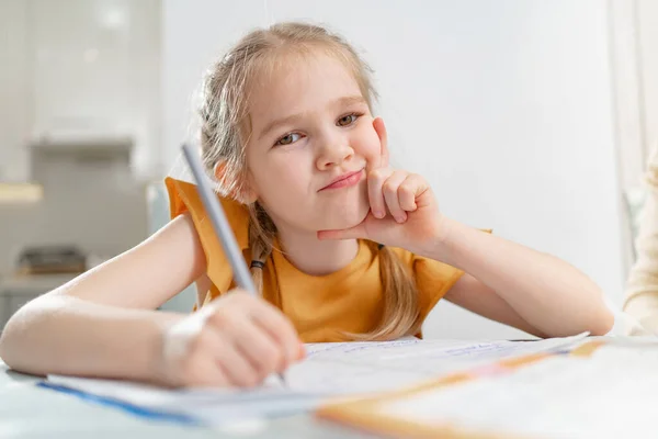 Ein nachdenkliches kleines Schulmädchen macht ihre Hausaufgaben. — Stockfoto