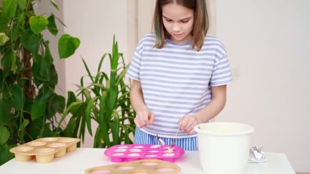 Adolescente chica pone la masa en forma de silicona para cupcakes en casa. — Vídeo de stock