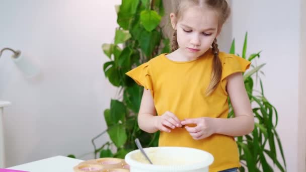 Flicka i en t-shirt sätter degen och choklad i silikon form för cupcakes. — Stockvideo