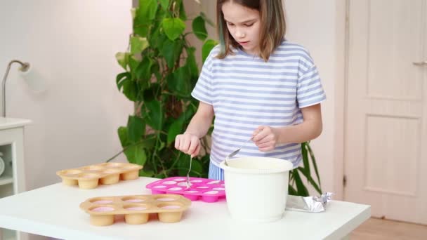 Teenage girl puts the dough in silicone form for cupcakes at home. — Stock Video