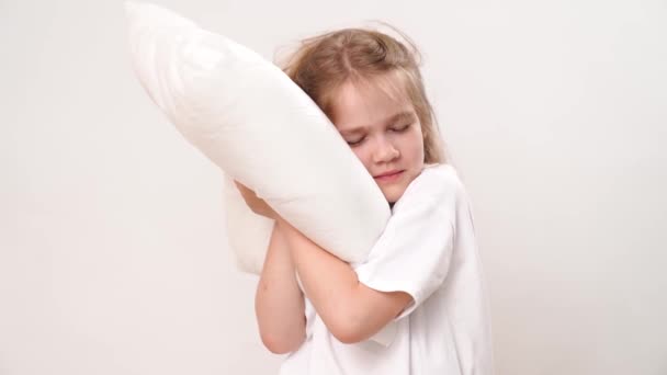 Ένα Χαριτωμένο Νυσταγμένο Κορίτσι Αγκαλιάζει Ένα Μαξιλάρι Λευκό Φόντο Πρώιμη — Αρχείο Βίντεο