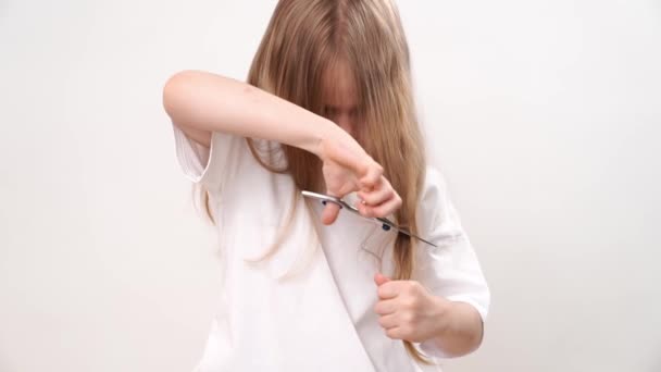 子供の女の子は白い背景にはさみで長い髪を耳にします 赤ちゃんのためのファッショナブルなヘアカット 美容師さん 子供用のイタズラ — ストック動画