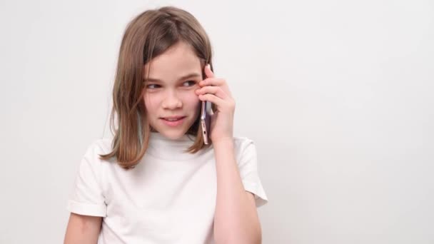 The teenage girl talking on smartphone and laughs on a white background. — Stok video