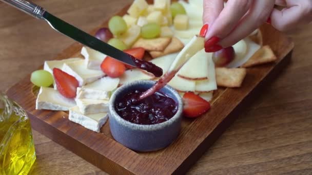 Fromage assorti de fruits sur planche de bois. tremper les mains morceau de fromage dans la confiture. — Video