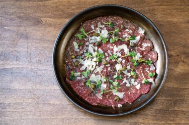 Mikro yeşil, kapari ve parmesanlı kurutulmuş et tabağı. Ziyafette et yemekleri ve mezeler servis ediliyor. Masaya servis..