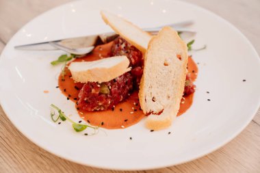 Soslu tartar, mikroyeşil ve beyaz tabakta ekmek. Ziyafette atıştırmalık ve atıştırmalık ikram ediyorum..