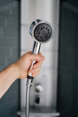 Bir erkeğin eli, duştaki sulama kutusunu tutar. Banyo ve duş için modern tesisat. Ev eşyaları deposu.