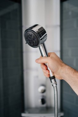 Bir erkeğin eli, duştaki sulama kutusunu tutar. Banyo ve duş için modern tesisat. Ev eşyaları deposu.
