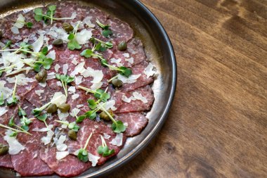 Mikro yeşil, kapari ve parmesanlı kurutulmuş et tabağı. Ziyafette et yemekleri ve mezeler servis ediliyor. Masaya servis..