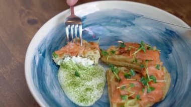 Mavi tabakta somon ve beyaz soslu Viyana waffle 'ı bıçak ve çatalla yenir. Bir kafe ve restoranda kahvaltı servisi. Masa servisi ve ziyafet için tabak servisi..