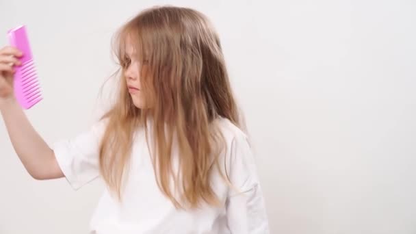 子供の女の子は長いと白い背景に絡んだ髪を結合します 子供の髪のケアのための化粧品 — ストック動画