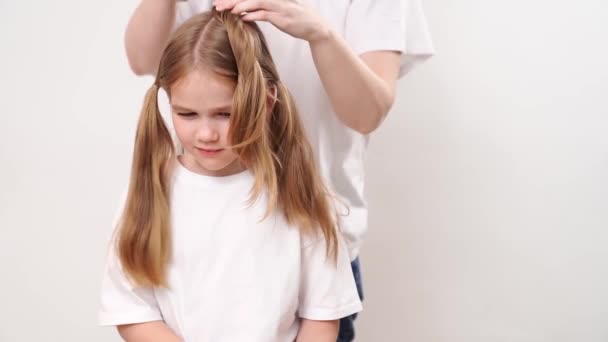 妈妈在白色背景上做一个小女孩的头发 妈妈是个理发师 在美容院省钱 洗发水和儿童用化妆品 — 图库视频影像