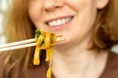 Hazır Asya yemeği teslimatı. Kadın, kız sebzeli erişte ve suşi çubuklarıyla deniz ürünleri yiyor. Lezzetli yemek. Telefon üzerinden ya da internetten yemek sipariş et.. 