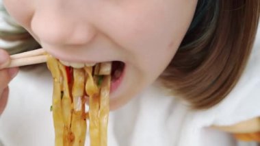 Hazır Asya yemeği teslimatı. Kadın, kız sebzeli erişte ve suşi çubuklarıyla deniz ürünleri yiyor. Lezzetli yemek. Telefon üzerinden ya da internetten yemek sipariş et.. 