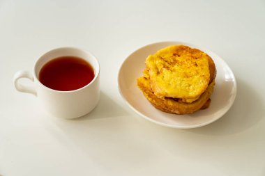 Bir fincan çay ve ekmek ve yumurta, beyaz bir masada bir tabakta. Lezzetli, hızlı ve basit bir kahvaltı..