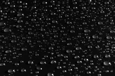 Siyah arka planda bir damla su. Doku. Yüzeyde çiy taneleri. Nemlendirici. yağmur veya sisten sonra damlalar.