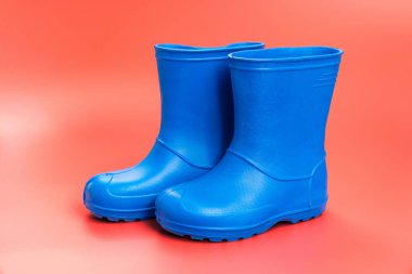 Pembe arka planda mavi lastik çizmeler. Yağmurlu hava ve su birikintileri için ayakkabılar. Ayakkabı dükkanı. Ayaklarını nemden ve pislikten koru..