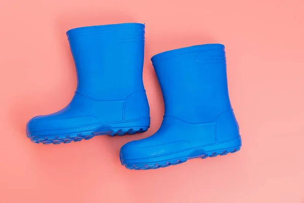 粉色背景上的蓝色橡胶靴 雨天穿的鞋子和水坑 保护你的脚免受湿气和污垢的影响 — 图库照片