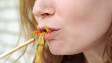 Hazır Asya yemeği teslimatı. Kadın, kız sebzeli erişte ve suşi çubuklarıyla deniz ürünleri yiyor. Lezzetli yemek. Telefon üzerinden ya da internetten yemek sipariş et.. 