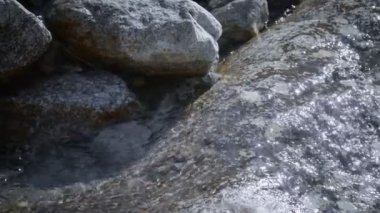 Temiz, dağ içme suyu büyük bir taştan aşağı akar.