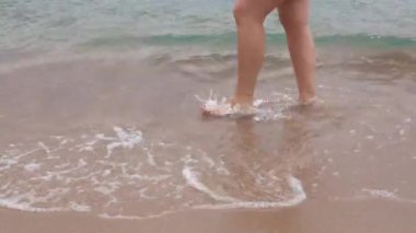 Dişi bacakları deniz kıyısında yürüyor.