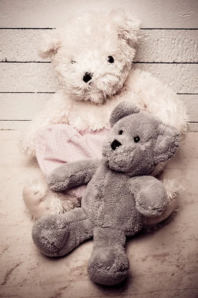 Teddy ursos sentados no chão de madeira branco com bom fundo solitário — Fotografia de Stock