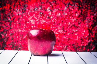 Beyaz ahşap bir masa üzerinde kırmızı elma. Ufuk arka plan bukeh