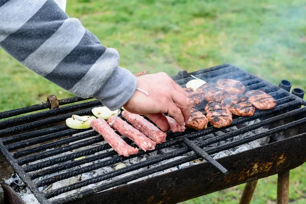 Barbecue extérieur. Hommes boulettes de viande cuites à la main et oignons sur le gril . — Photo