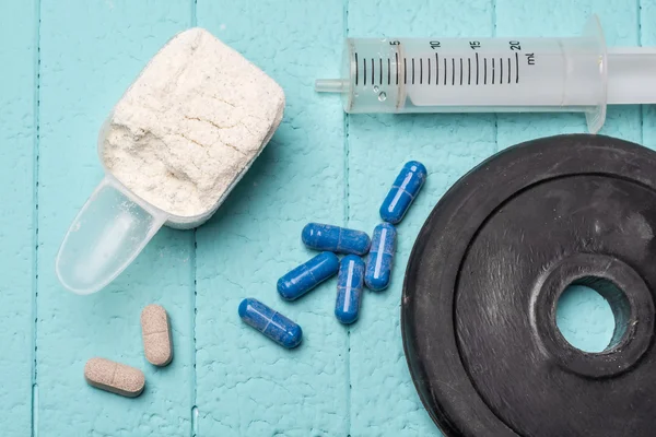 Container van melk wei-eiwit, lege injectie en pillen. Close-up. Blauwe achtergrond — Stockfoto