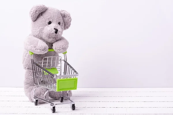 Kleiner Einkaufswagen und ein Teddybär. Konzeptbild für den Verkauf von Spielzeug oder Kinderfantasien — Stockfoto