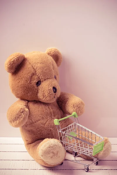 Kleiner Einkaufswagen und ein Teddybär. Konzeptbild für den Verkauf von Spielzeug oder Kinderfantasien — Stockfoto