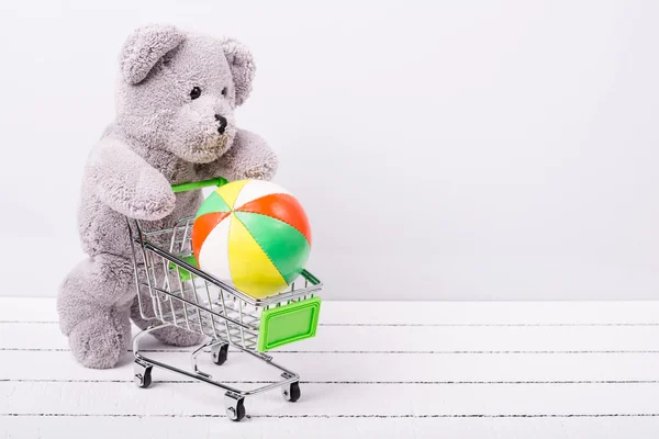 Kleiner Einkaufswagen und ein Teddybär. Konzeptbild für den Verkauf von Spielzeug oder Kinderfantasien — Stockfoto