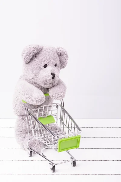 小さなショッピング カートとテディベア。玩具または子供の空想の販売のための概念図 — ストック写真